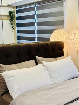 a bed with white pillows and a brown couch at Sea Residences in Manila