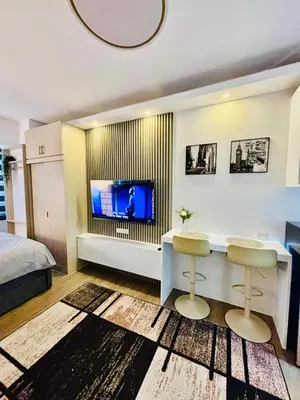 a living room with a television and two stools in front of a bed at Sea Residences in Manila