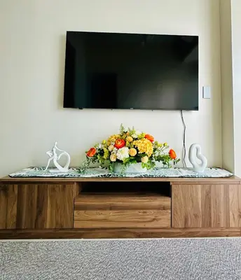 a vase of flowers sitting on top of a entertainment center at The Bloom by Y&Y Condo at Bayshore Res Resort in Manila