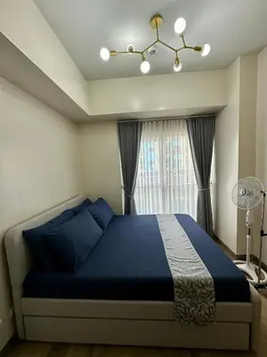 a bedroom with a blue bed and a window at The Bloom by Y&Y Condo at Bayshore Res Resort in Manila