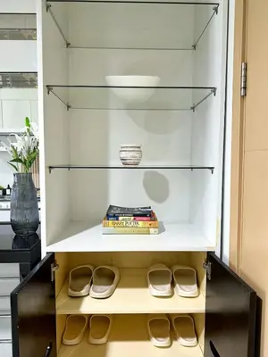 a glass cabinet with books and shoes in it at New Cozy 2-bedroom deluxe condo for 5 pax in MOA in Manila