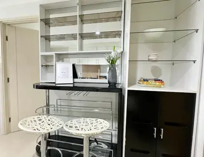 a kitchen with glass shelves and two stools at New Cozy 2-bedroom deluxe condo for 5 pax in MOA in Manila