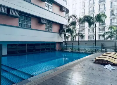 a swimming pool in front of a building at Aura Zen Suites condotel in Manila