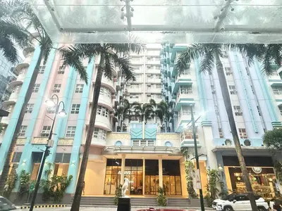a large building with palm trees in front of it at Aura Zen Suites condotel in Manila