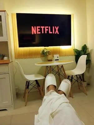 a man laying on the floor in front of a netflix sign at Lovers' Cozy 1BR Condo Near Mall and Airport with Free Netflix Premium and 100 MBPS WiFi in Manila