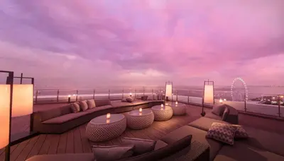 a rooftop deck with couches and candles on a balcony at Conrad Manila in Manila