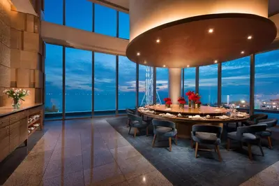 a dining room with a table and chairs and large windows at Conrad Manila in Manila