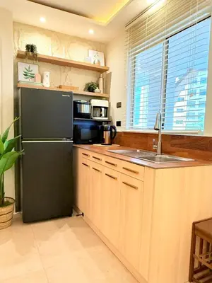 a kitchen with a black refrigerator and wooden cabinets at 1-Bedroom Cozy Haven Sorrento Oasis in Manila
