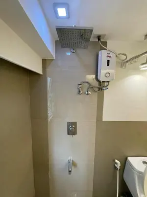 a bathroom with a toilet and a dispenser on the wall at Spacious 1BR Loft with Flex Room in BGC in Manila
