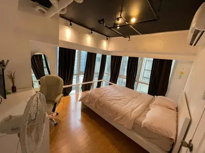 a bedroom with a bed and a chair and windows at Spacious 1BR Loft with Flex Room in BGC in Manila