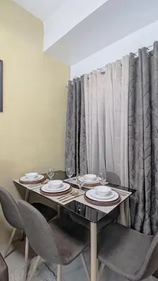 a dining room table with plates and wine glasses at Green 2 Residences Tower 2 Petes Place in Dasmariñas