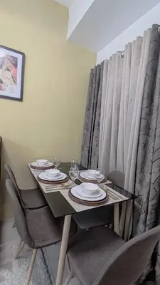 a table with chairs and plates and wine glasses at Green 2 Residences Tower 2 Petes Place in Dasmariñas