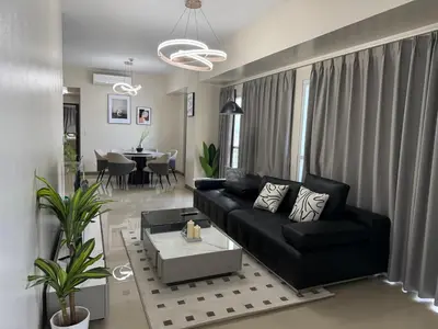 a living room with a black couch and a table at HomeMadeLuxury 3 Bedrooms Seaview Sunset View Near Manila Airports Okada MOA in Manila