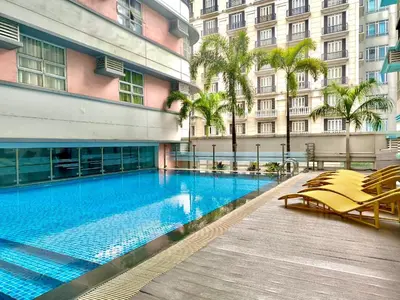 a large swimming pool with chairs and a building at NAIA 101 Condotel Newport Luxe Stay Pasay in Manila