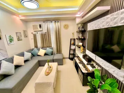 a living room with a couch and a large flat screen tv at NAIA 101 Condotel Newport Luxe Stay Pasay in Manila
