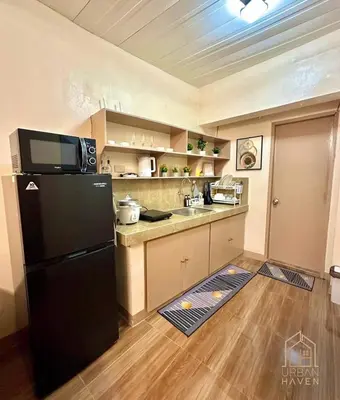 a kitchen with a black refrigerator and wooden floors at Staycation in Alabang in Manila