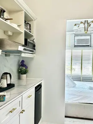 a kitchen with white cabinets and a bed in a window at Studio Two Condominium, Alabang - OLIVE in Manila