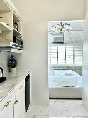 a white kitchen with a bed in a window at Studio Two Condominium, Alabang - OLIVE in Manila
