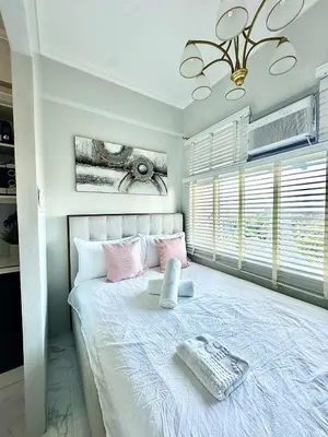a bedroom with a large bed with pink pillows at Studio Two Condominium, Alabang - OLIVE in Manila