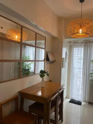 a dining room with a wooden table and two lights at Smdc Coast Resideces in Manila
