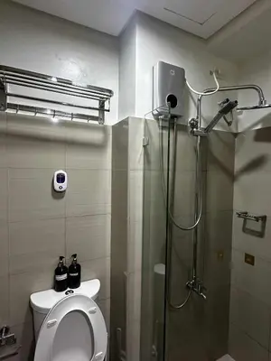 a bathroom with a shower stall and a toilet at Cozy MOA Condo Perfect for 2 in Manila