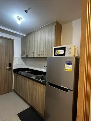 a kitchen with a stainless steel refrigerator and wooden cabinets at Cozy MOA Condo Perfect for 2 in Manila