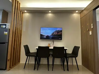a dining room table with chairs and a tv on the wall at Cozy MOA Condo Perfect for 2 in Manila