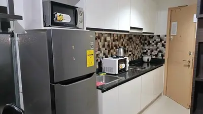 a kitchen with a refrigerator and a microwave at Basic one-bedroom condo at Sea Residences in Manila