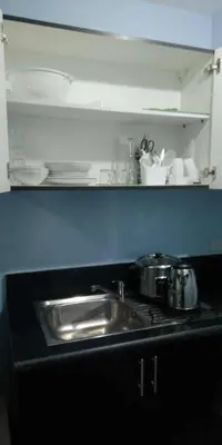 a kitchen sink with pots and pans on a counter at 1 bedroom condo unit for 4 with balcony, pool, WIFI at Newport across NAIA T3 in Manila