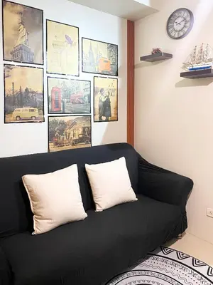 a black couch in a room with pictures on the wall at 1BR- Axinite walking distance to MOA, PICC, SMX, Worldtrade near NAIA and Star City in Manila
