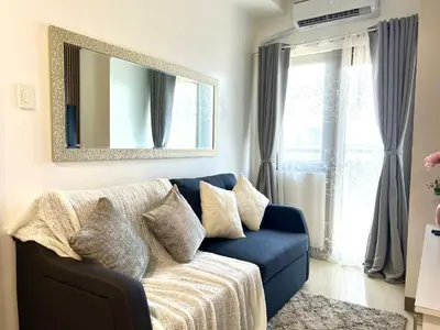 a blue couch in a living room with a mirror at Suite Serenity at S residences in Manila