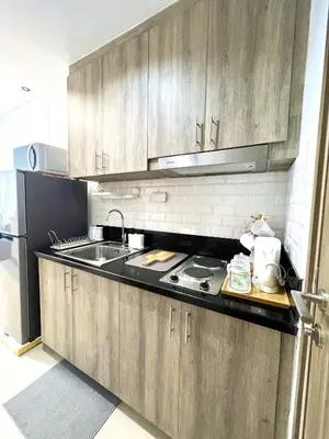 a kitchen with wooden cabinets and a sink and a stove at Suite Serenity at S residences in Manila