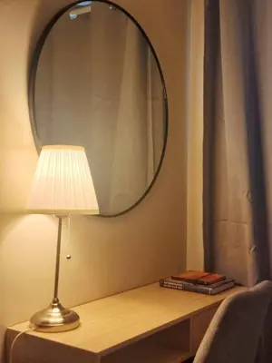 a lamp sitting on a table with a mirror at Your Stylish City Escape in Park Mckinley West with Breathtaking Views in Manila
