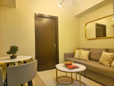 a living room with a couch and a table and a mirror at Your Stylish City Escape in Park Mckinley West with Breathtaking Views in Manila