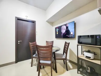a dining room with a table and chairs and a tv at Modern 1 br in Park Mckinley West with Breathtaking view fast internet in Manila