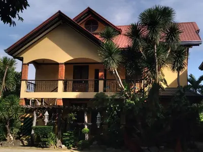 a house with palm trees in front of it at La Traviesa Hotel Resort in General Trias