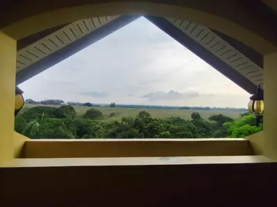 a window with a view of a field and trees at La Traviesa Hotel Resort in General Trias