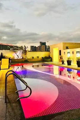 a swimming pool with pink lights on a building at Mariz Suites in Manila