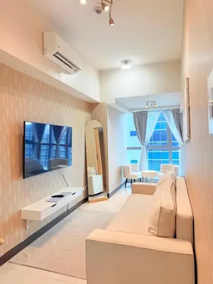 a living room with a couch and a tv on a wall at Uptown Parksuites Tower 1 in Manila