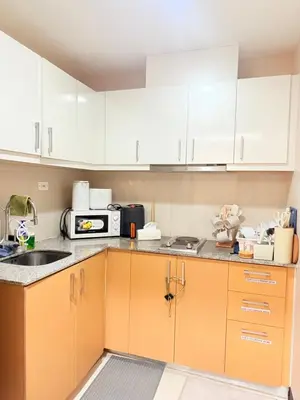 a kitchen with white cabinets and a microwave at Uptown Parksuites Tower 1 in Manila