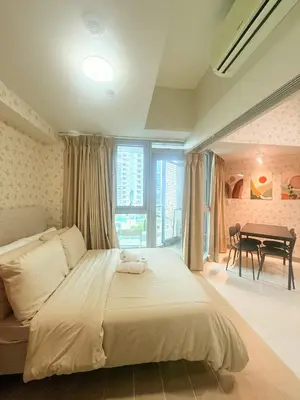a bedroom with a large bed and a table at Uptown Parksuites Tower 2 in Manila