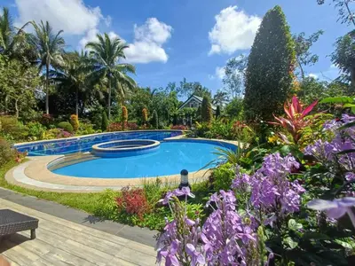 a swimming pool in a garden with purple flowers at El Casa Azul in Amadeo