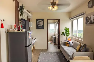 a living room with a couch and a refrigerator at Family-Friendly 2BR Staycation near Nuvali & Enchanted Kingdom in Puting Kahoy