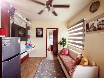 a living room with a couch and a kitchen at Family-Friendly 2BR Staycation near Nuvali & Enchanted Kingdom in Puting Kahoy
