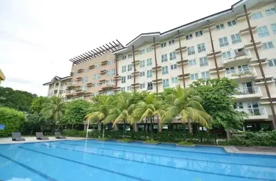 a hotel with palm trees in front of a pool at Comfortable 3-Bedroom Stay in Pasig The Rochester in Manila
