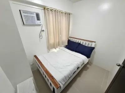 a small bed in a white room with a window at Comfortable 3-Bedroom Stay in Pasig The Rochester in Manila