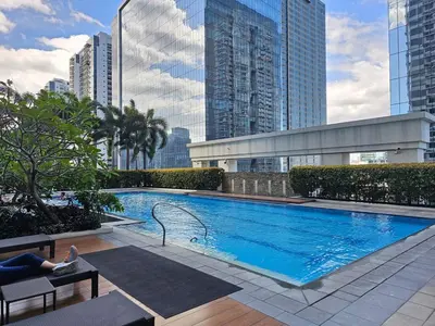 a woman laying on a bench next to a swimming pool at The Infinity Towers in BGC - Spacious 2 Bedroom - View, Washer, Fast WiFi in Manila