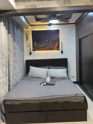 a bedroom with a large bed with a ceiling fan at JOYCE LARA Staycation in Manila