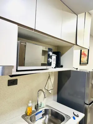 a kitchen with a sink and a microwave at One-bedroom condo within the city at S Residences in Manila