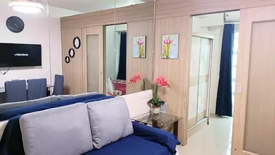 a living room with blue pillows on a couch at Pool view from one-bedroom condo at Shore Residence in Manila
